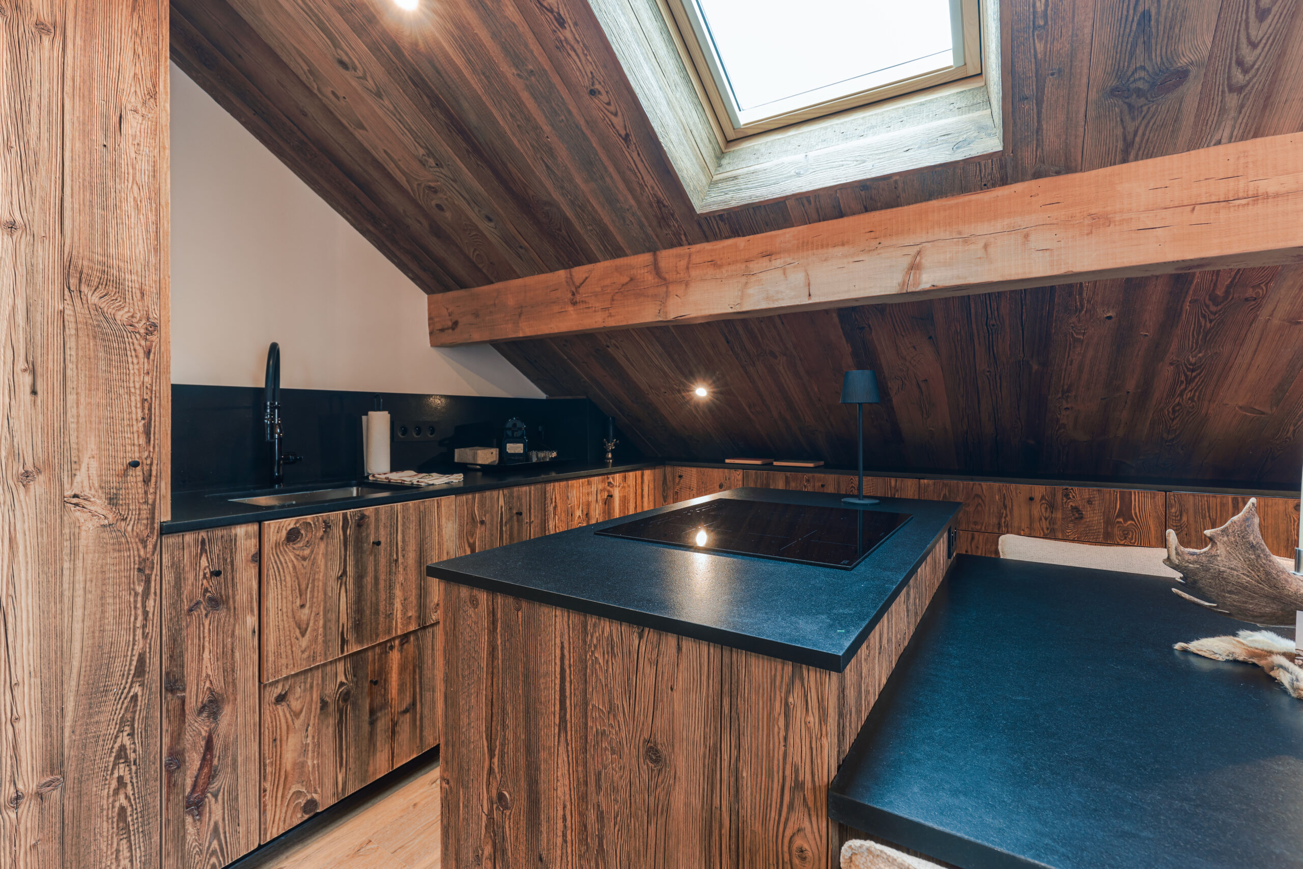 Cuisine moderne équipée et coin repas chaleureux sous les poutres apparentes, Megève.