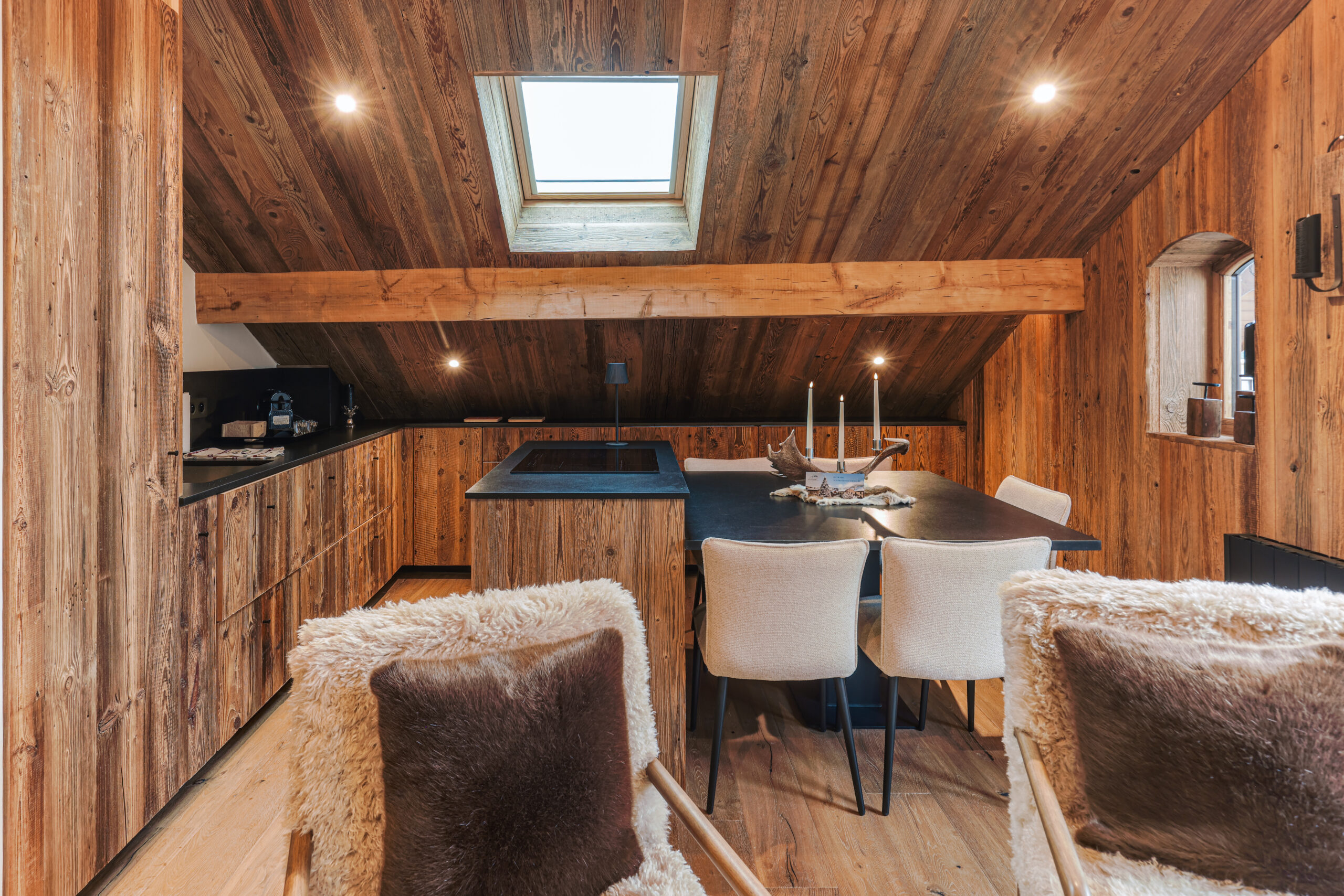 Cuisine moderne équipée et coin repas chaleureux sous les poutres apparentes, Megève.