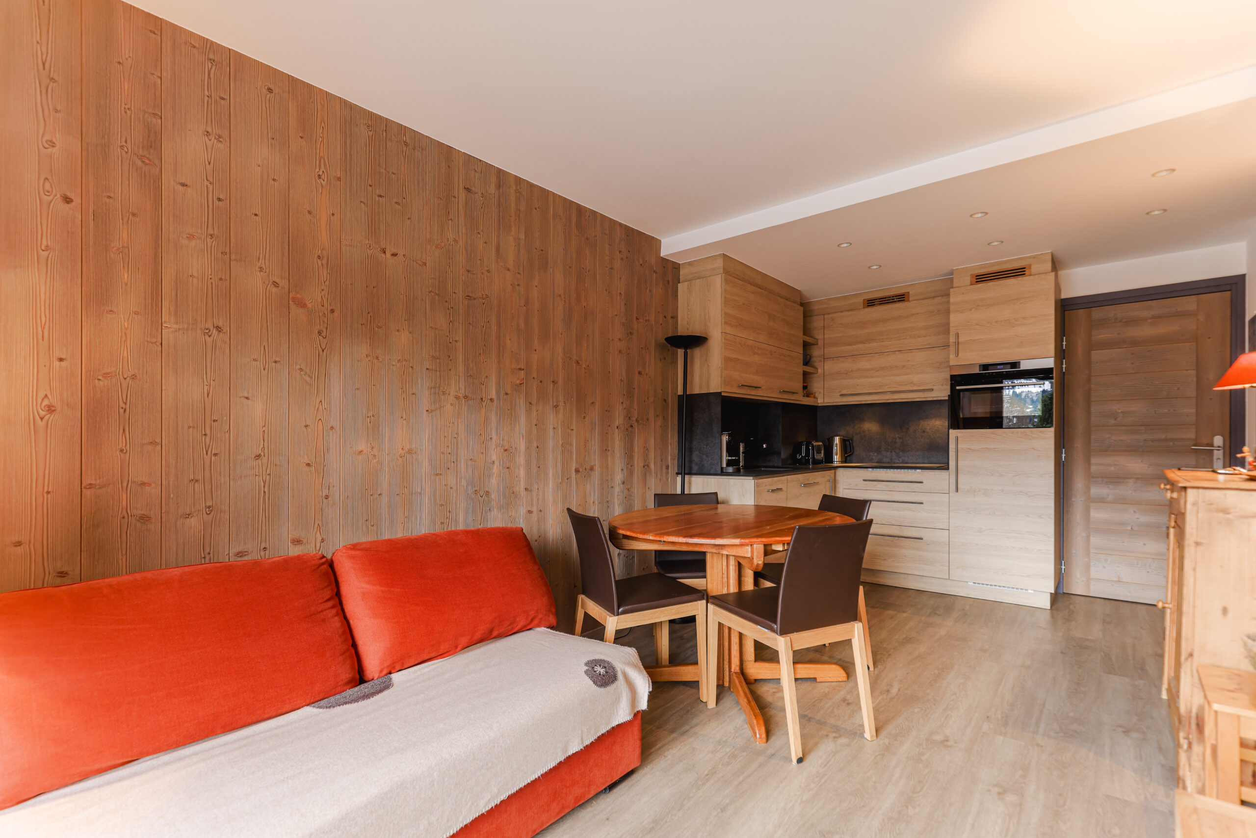 Pièce de vie lumineuse et chaleureuse avec canapé convertible et accès direct au balcon, Megève. Espace salle à manger convivial pour 4 personnes dans un appartement de standing au Jaillet.