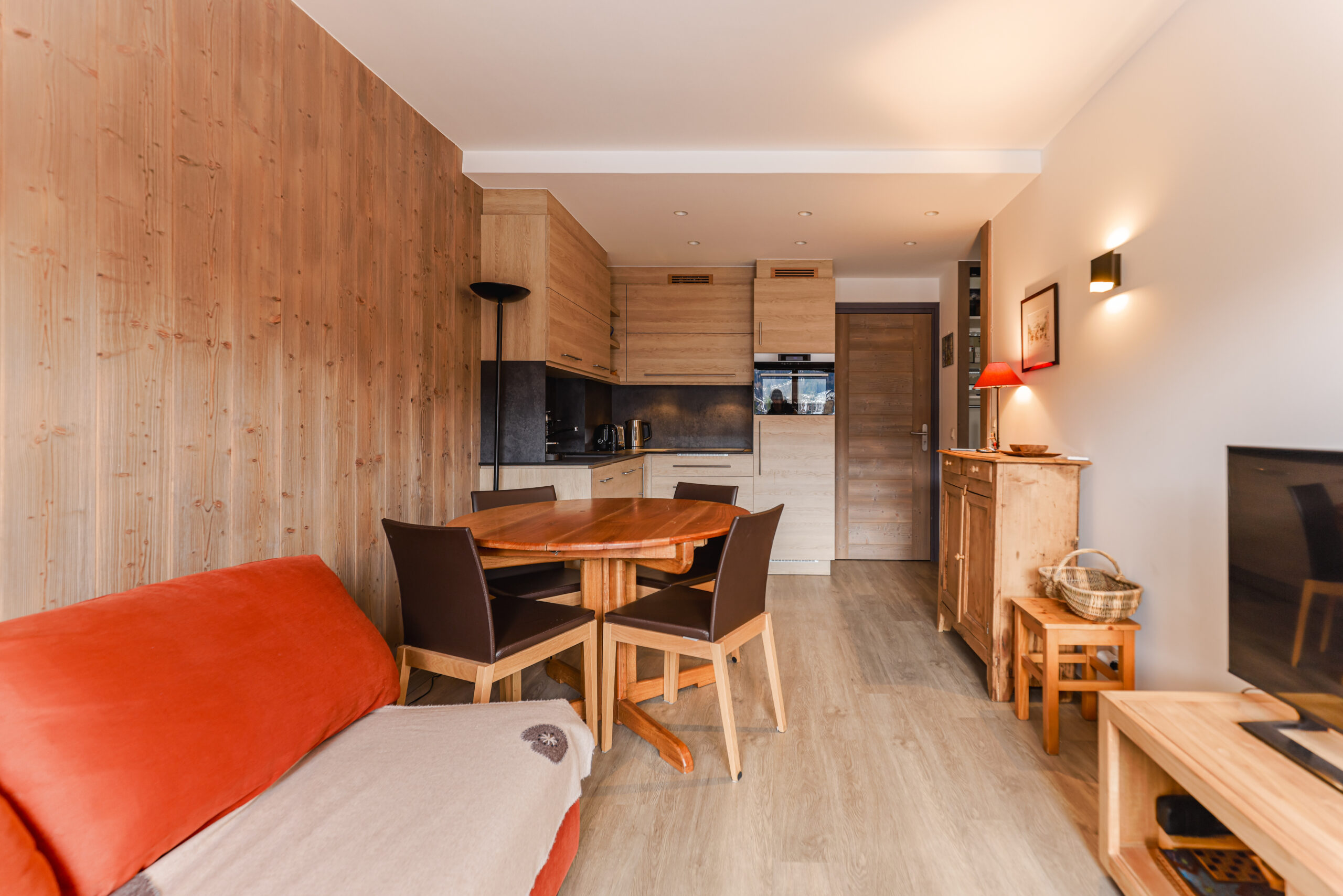 Pièce de vie lumineuse et chaleureuse avec canapé convertible et accès direct au balcon, Megève. Espace salle à manger convivial pour 4 personnes dans un appartement de standing au Jaillet.