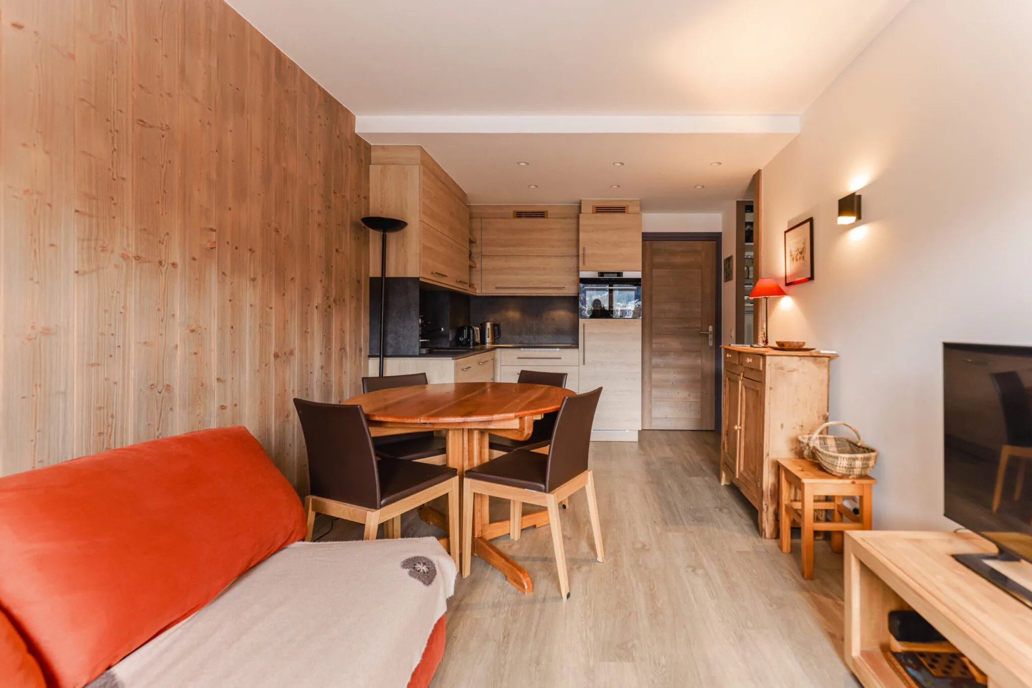 Pièce de vie lumineuse et chaleureuse avec canapé convertible et accès direct au balcon, Megève. Espace salle à manger convivial pour 4 personnes dans un appartement de standing au Jaillet.